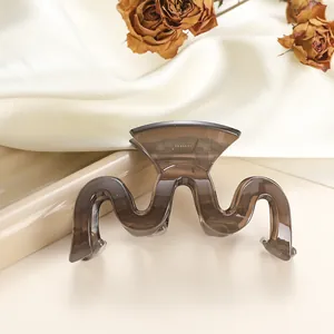 Detail of translucent dark brown wave hair claw clip on elegant white satin background