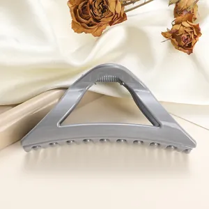 Detail of grey-blue triangular hair claw clip with glossy finish on silk background