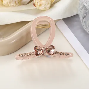 Detalle de pinza para el pelo rosa con lazo de corazón de cristal y pedrería champán