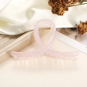 Detail of pink translucent large shark clip with golden spring on elegant silk background