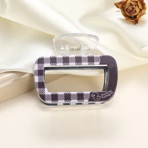 Detail of purple checkered acrylic hair claw clip with Duckling Teenagers logo on silk