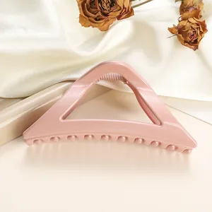 Macro shot of large glossy pink triangle hair claw clip with smooth resin finish