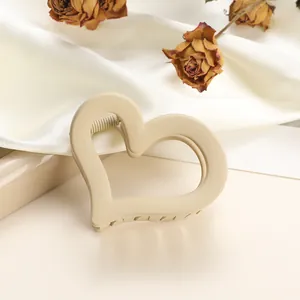 Close-up of heart-shaped matte hair claw clip in beige on white silk with dried roses