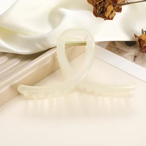 Detail of cream shark hair clip with gold spring on elegant white silk background