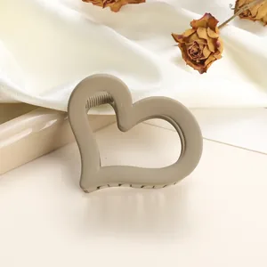 Close-up of heart-shaped matte hair claw clip in khaki on silk with dried roses