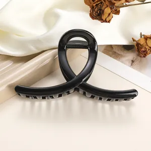 Glossy black shark hair claw clip with crossed lines on elegant champagne satin fabric