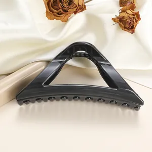 Detail of a large triangular black shark hair claw clip with glossy finish and metal spring