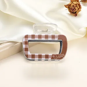 Detail of small checkered acrylic hair claw clip with duckling print on silk background