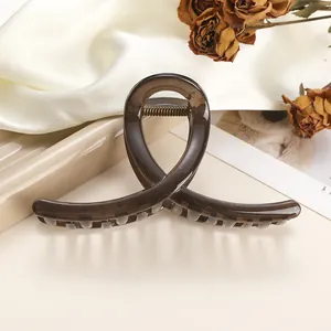 Detail of a large amber resin hair claw clip with cross twist design on silk background