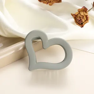 Close-up of heart-shaped matte hair claw clip in sage green on silk with dried roses