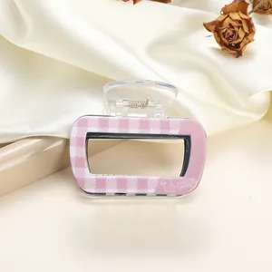 Detail of pink and white checkered acrylic hair claw with metal spring and duck logo