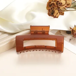 Detail of amber translucent square hair claw clip with metal spring on white silk