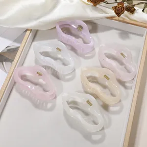 Lot de six pinces à cheveux ondulées en résine aux tons pastels nacrés sur plateau bois
