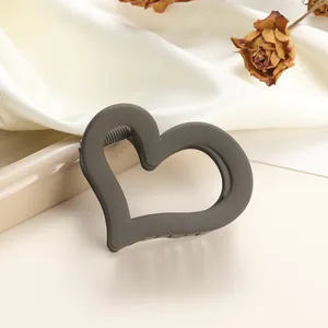 Detailed close-up of a matte dark grey hollow heart hair claw on soft silk fabric