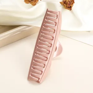 Close-up of a glossy peach pink large hair claw clip on silk fabric with dried flowers