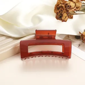 Close-up of a large amber hair claw clip on silk fabric with floral decor accents