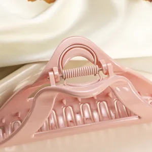 Detail of a large pink hair claw clip showing glossy finish and silver metal spring