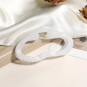 Détail de la grande pince à cheveux blanc crème avec ressort en métal doré élégant