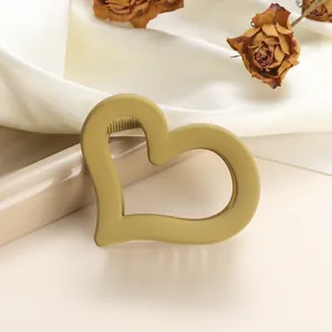 Close-up of matte heart-shaped hair claw clip in mustard yellow on white satin