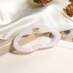 Détail de la pince à cheveux en résine rose avec ressort doré et paillettes
