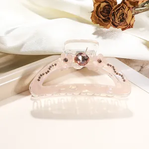 Detail of pink resin hair claw clip with large center diamond and floral rhinestone patterns