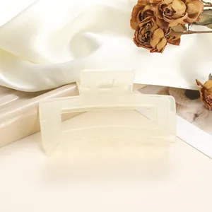 Detail of cream rectangular hair claw clip with metal spring on silk background