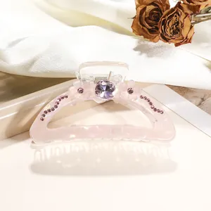Detailed close-up of pink translucent hair claw with 3D flowers and sparkling rhinestones