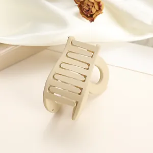 Detailed close-up of a cream matte heart-shaped hair claw clip on soft white fabric