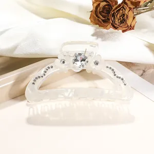 Macro shot of 9cm iridescent hair claw clip with white floral motifs and crystal details