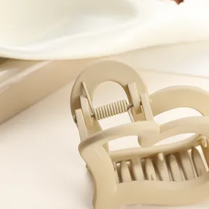 Close-up of minimalist beige matte heart hair claw clip with smooth hollow lines