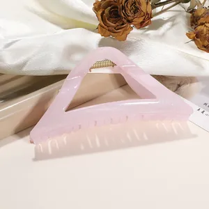 Detail of pink glitter triangle hair claw clip with golden spring on satin background