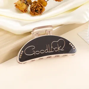 Detail of 9cm hair claw clip with GoodLuck lettering and rhinestones on satin