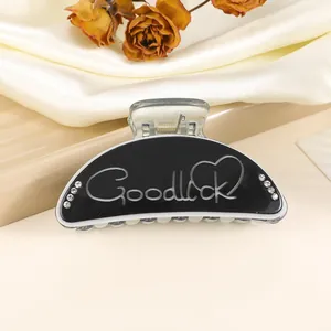 Detailed macro view of black medium shark hair claw clip with Goodluck engraving