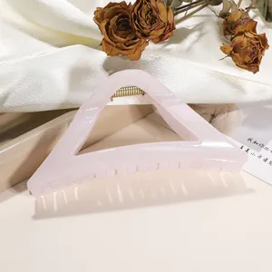 Macro detail of large pale pink triangular shark clip with subtle shimmer finish