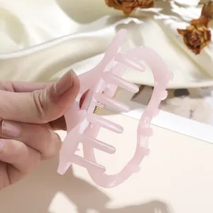 Détail de la pince à cheveux rose nacré montrant les vagues et le ressort doré