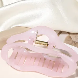 Gros plan d'une pince à cheveux rose pailletée avec ressort doré sur soie blanche