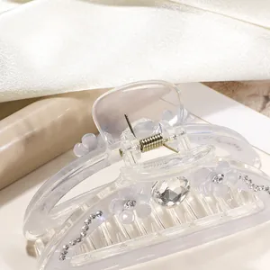 Detail shot of a transparent 9cm claw clip with white floral accents and sparkling rhinestones