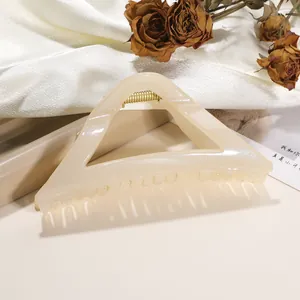 Close-up of a cream triangle shark hair claw clip with fine glitter and gold spring