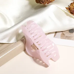 Détail d'une grande pince à cheveux rose pâle translucide avec paillettes sur de la soie