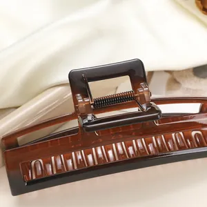 Detailed close-up of a large amber gradient square hair claw clip on soft satin fabric