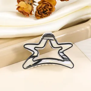 Detail of star-shaped hair claw clip with black and white marble pattern on silk