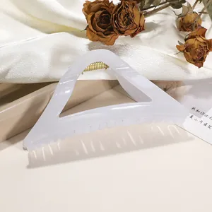 Macro detail of pearl white triangle hair claw clip with golden spring on silk background