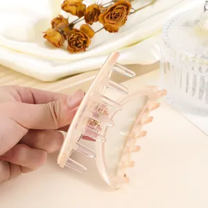 Detail of a translucent peach pink acrylic hair claw clip with strong metal spring