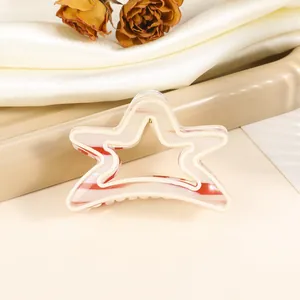 Detailed close-up of a star-shaped hair claw clip with red and white striped patterns