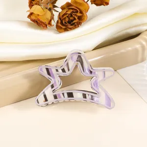 Detail view of purple and black striped star-shaped hair claw clip on silk background