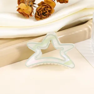 Close-up of hollow star hair claw with pearlescent finish on cream tray and silk fabric