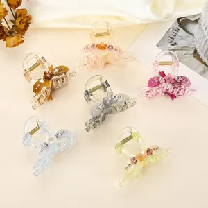 Florale Acryl-Haarklammern mit Strass in sechs Farben auf elegantem cremefarbenem Stoff