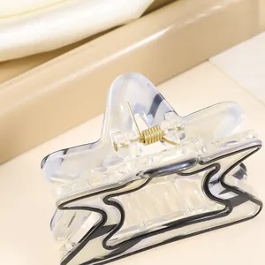 Close-up of a translucent star-shaped hair claw clip with golden metal spring detail