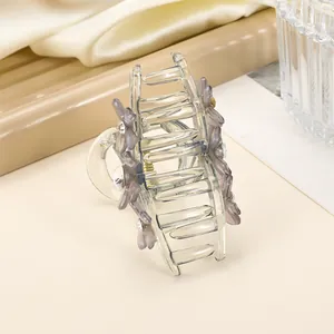 Close-up of a large purple acrylic hair claw with floral accents and sparkling rhinestones