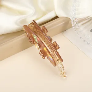 Detail van een amberkleurige bananenclip met iriserende finish en bloemsteentjes